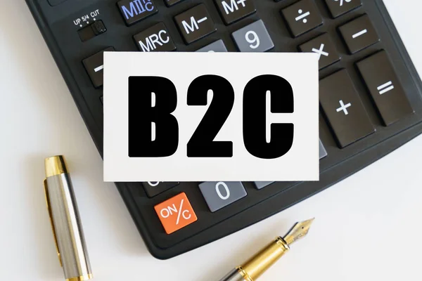 Business and finance concept. On the table there is a pen, a calculator and a business card on which the text is written B2C. BUSINESS TO CONSUMER