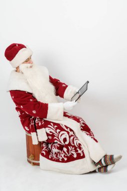 Noel ve Yeni Yıl konsepti. Noel Baba tabletle çalışır. İzole edilmiş arkaplan