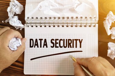 İş ve finans kavramı. Bir adam not defterine DATA GÜVENLİK metni yazar. Elinde bir not defteri ve buruşuk bir kağıt vardı..