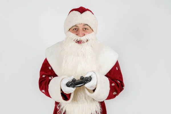 休日やクリスマスのコンセプト サンタクロースは手にジョイスティックを持ち コンピュータゲームをプレイする 白に隔離された — ストック写真