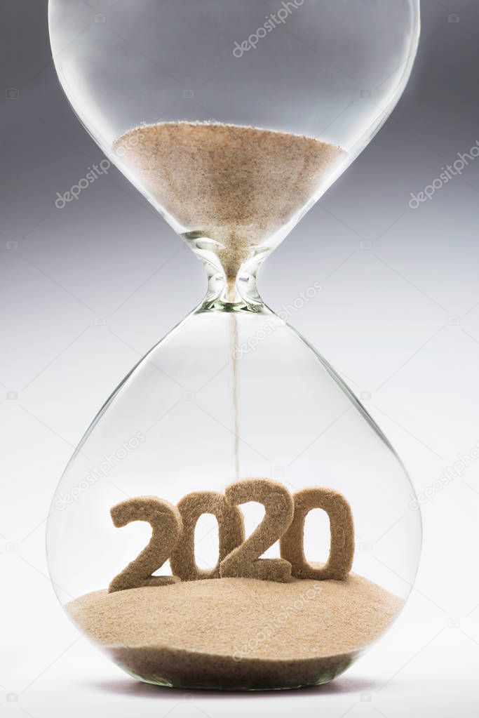New Year 2020 concept with hourglass falling sand taking the shape of a 2020