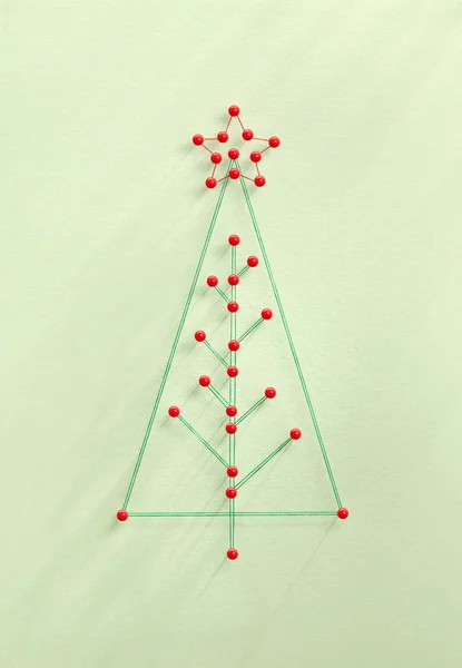 Celebrating Christmas together. Network of pins and threads in the shape of a Christmas tree symbolising sharing and community.