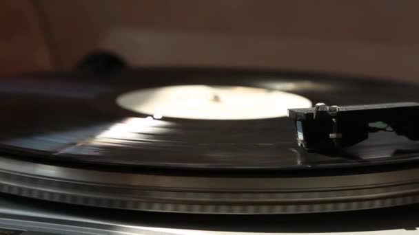 灰色の蓄音機 黒いレコードが回転しています 光の光の中で 針が立ち上がる 側面図 — ストック動画