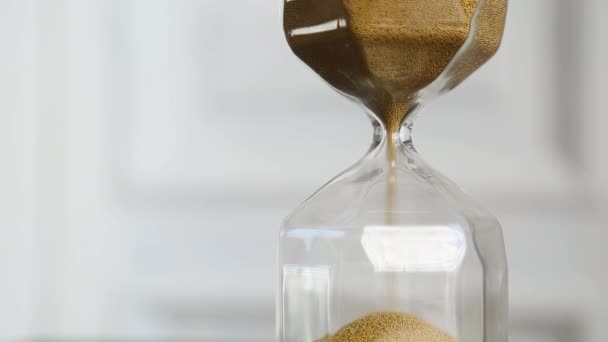 Transparente Sanduhr auf weißem Hintergrund. Goldener Sand ergießt sich. — Stockvideo