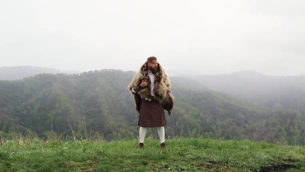 Człowiek Wąsy Brodą Stoi Szczycie Góry Kilt Skóry Niedźwiedzia Plecach — Wideo stockowe