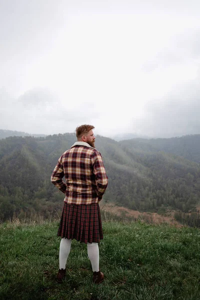 Man kilt with mustache beard mountain. looking back. snow. fog Caucasian Royalty Free Stock Images