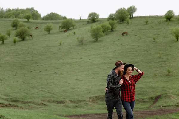 man woman are holding hands, walking around the horse