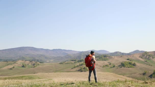 バックパックを持つひげの口ひげを持つ男は、山の夏が周りを見て行く. — ストック動画