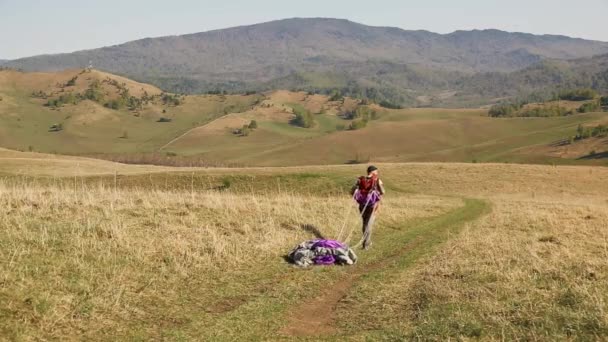Ο άνθρωπος μούσι μουστάκι κουβαλάει ένα αλεξίπτωτο σε ένα φόντο βουνών — Αρχείο Βίντεο