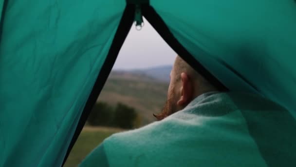 Man lämnar grönt tält, ovanpå ett berg, skog, oskärpa — Stockvideo