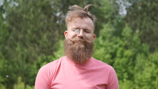 Muž s motýlím hmyzem na obličeji, legrační okamžik, hipster s úsměvem, v růžovém tričku, — Stock video