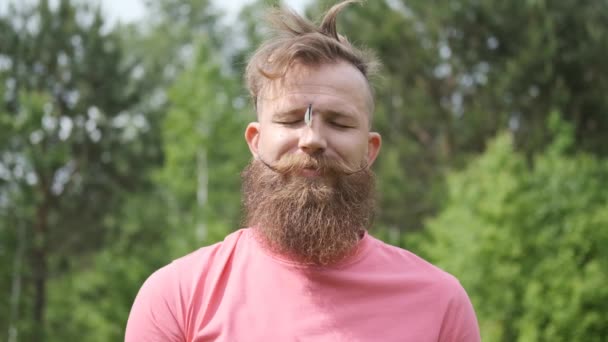 Mann im Wald mit Schmetterling, Hipster im rosa T-Shirt, Schmetterling im Gesicht, lustiger Moment — Stockvideo