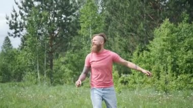 Adam çayırda kelebek yakalar, pembe tişört ve şortlu hipster, neşeli ruh hali.