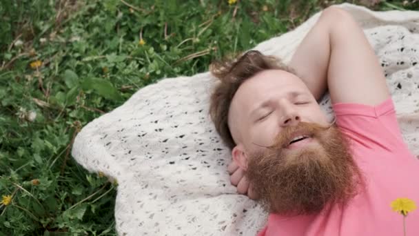 Man met paardebloem ligt in weide op gras, goed humeur, zonnig zomerweer — Stockvideo