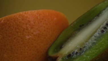 Çeşitli taze meyve, greyfurt, meyvenin üzerine su sıçraması, taze meyve suyu. Sarı arka planda izole edilmiş. Yavaş çekim.