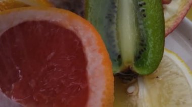 Çeşitli taze meyve, greyfurt, meyvenin üzerine su sıçraması, taze meyve suyu. Sarı arka planda izole edilmiş. Yavaş çekim.