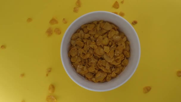 Cereais de pequeno-almoço são derramados em uma tigela branca, isolado em um fundo amarelo — Vídeo de Stock