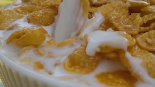 Primer plano, cereales de desayuno en un tazón blanco, leche vertiendo en un tazón de copos de maíz , — Vídeo de stock