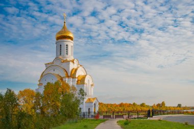 Bulutlu bir gökyüzüne karşı ağaçların arasında Ortodoks kilisesi