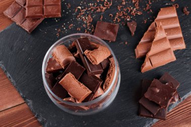 Karanlık ve sütlü çikolata bar ve siyah taş tahta parçaları. Tatlılar ve tatlılar bir kavram. Gıda arka plan üstten görünüm