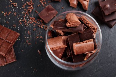 Karanlık ve sütlü çikolata bar ve siyah taş tahta parçaları. Tatlılar ve tatlılar bir kavram. Gıda arka plan üstten görünüm