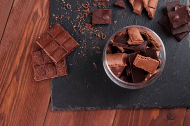 Karanlık ve sütlü çikolata bar ve siyah taş tahta parçaları. Tatlılar ve tatlılar bir kavram. Gıda arka plan üstten görünüm