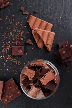 Karanlık ve sütlü çikolata bar ve siyah taş tahta parçaları. Tatlılar ve tatlılar bir kavram. Gıda arka plan üstten görünüm