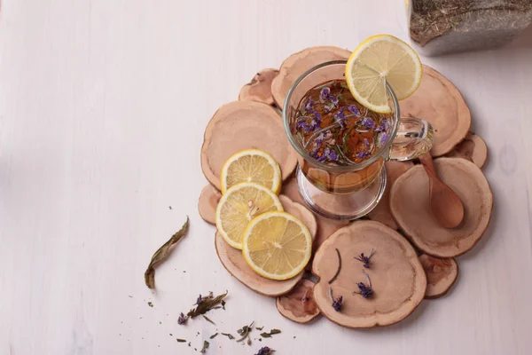 Top view of traditional Russian drink with honey, lemon and dried herbs in a glass cup on wooden table
