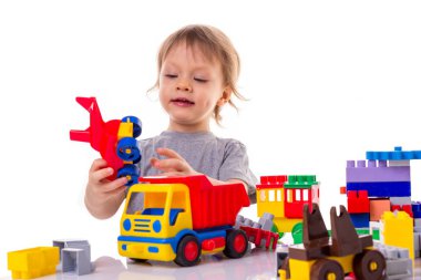 Küçük çocuk oyuncak blokları ve beyaz arka plan üzerinde izole arabalar oynamaya. Oyuncak Dükkanı satış ve erken çocuk geliştirme kavramı