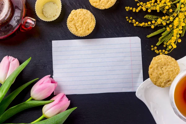 Kadınlar Günü tebrik kartı laleler, Mimoza, çay ve kek siyah taş tahta arka plan üzerinde.