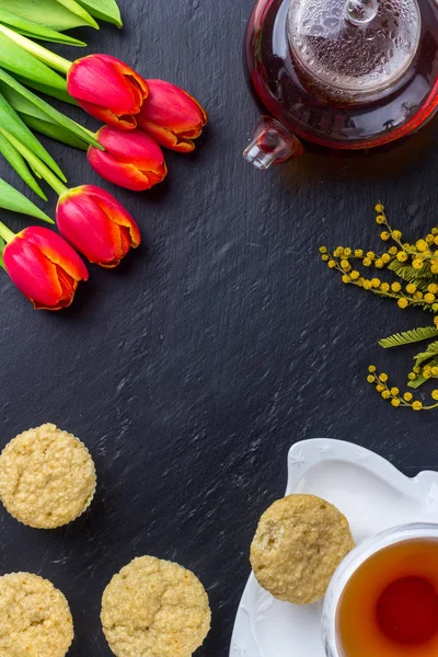 Kadınlar Günü tebrik kartı laleler, Mimoza, çay ve kek siyah taş tahta arka plan üzerinde.