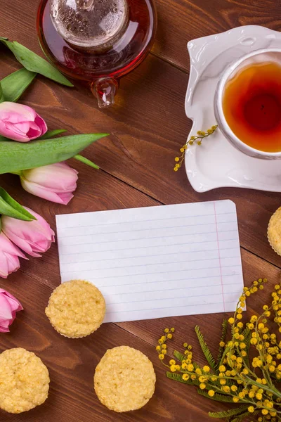 Kadınlar Günü tebrik kartı laleler, Mimoza, çay ve kek kahverengi ahşap zemin üzerinde.