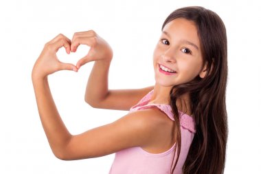 Beyaz dişleri ve koyu saçlı mutlu gülümseyen kız portresi elleri ile kalp işareti gösteren pembe giysiler giyen -beyaz izole