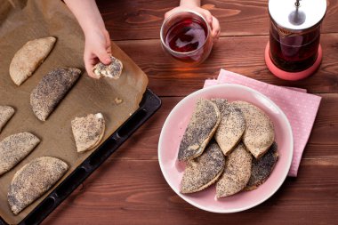 Çocuk eller geleneksel Rus tatlısını kuark, süzme peynir, kuru üzüm, sochni ya da sochniki turtası ya da pirozhki ile ahşap masa üzerinde sabah çayı ile birlikte pembe tabakta tutuyorlar.