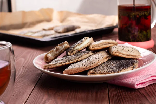 Kuark, süzme peynir, kuru üzüm, sochni ya da sochniki turtası ya da pembe tabakta haşhaş tohumlu pirozhki ve kahverengi ahşap masa üzerinde çay ile geleneksel Rus tatlısı.