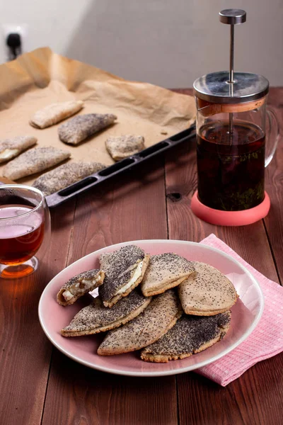 Kuark, süzme peynir, kuru üzüm, sochni ya da sochniki turtası ya da pembe tabakta haşhaş tohumlu pirozhki ve kahverengi ahşap masa üzerinde çay ile geleneksel Rus tatlısı.