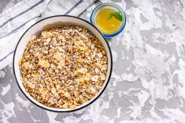 Beton arka plan üzerinde bal ile bir kase fındık ile Müsli - kuru kahvaltı.