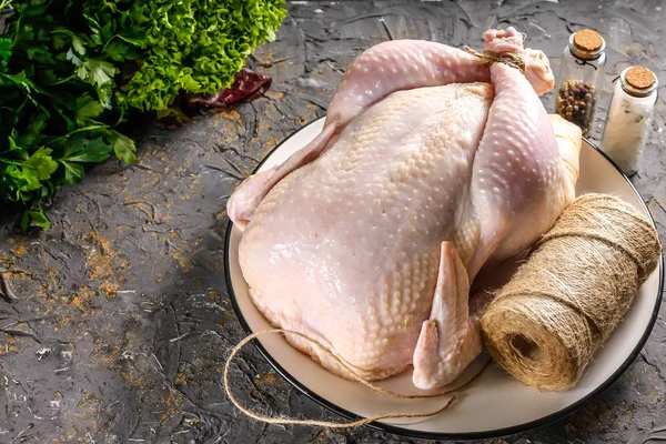 Fresh chicken for baking on a dish, spices with herbs and stone. Raw chicken is an ingredient for making food. Chicken for baking on Independence Day.