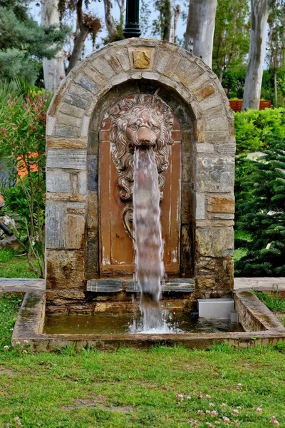 an arch made of stone with a lion head from which water flows