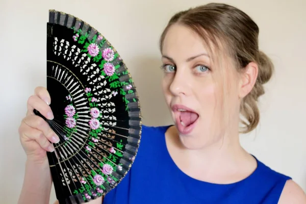 beautiful girl with a fan in his hand on a light background