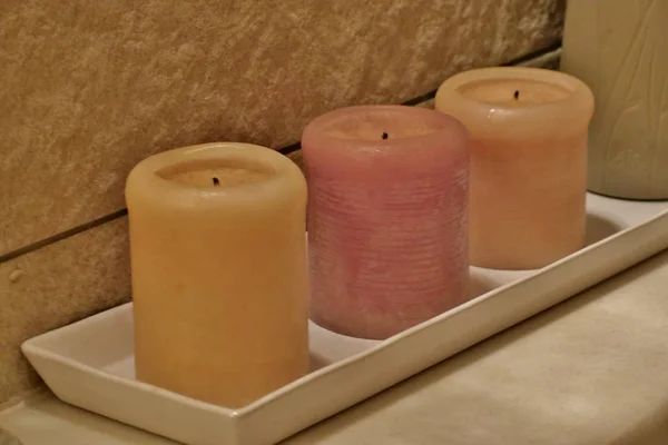 yellow and pink scented candles on a white stand close-up