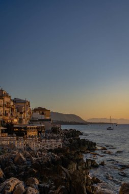 Cefalu 'nun kayalık sahillerinden gün batımı manzarası 