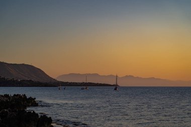 Cefalu 'nun kayalık sahillerinden gün batımı manzarası 
