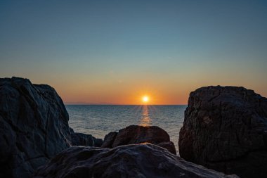Cefalu 'nun kayalık sahillerinden gün batımı manzarası 