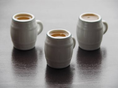 Koyu ahşap bir masa üzerinde açık bira standı ile üç dekoratif bira kupaları. Basit ve orijinal resim koyu bir arka plan üzerinde açık bira kupaları ile.