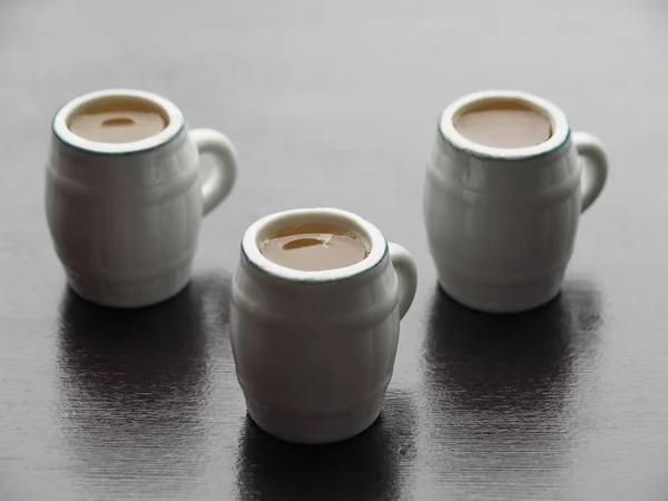 Three decorative beer mugs with light beer stand on a dark wooden table. Simple and original picture is with light beer mugs on a dark background.