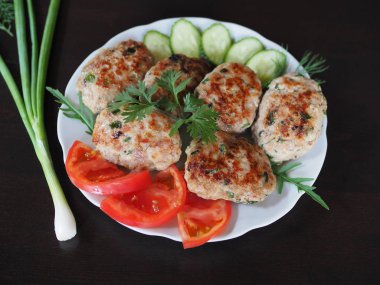 Diyet için otlar ve sebzeler ile pişirmek için altın bir kabuk ile Protein et çanak. Sebze ve otlar ile Doğranmış biftek koyu bir masada beyaz bir tabakta.
