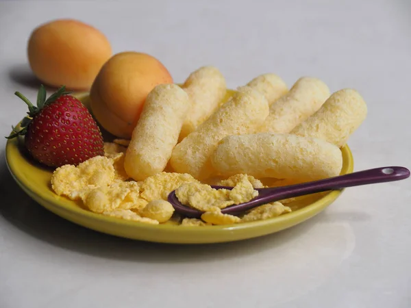 Corn sticks, cereals and fresh fruit are in the yellow plate. Perfect quick Breakfast for kids in the morning.