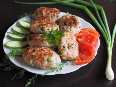 Diyet için otlar ve sebzeler ile pişirmek için altın bir kabuk ile Protein et çanak. Sebze ve otlar ile Doğranmış biftek koyu bir masada beyaz bir tabakta.