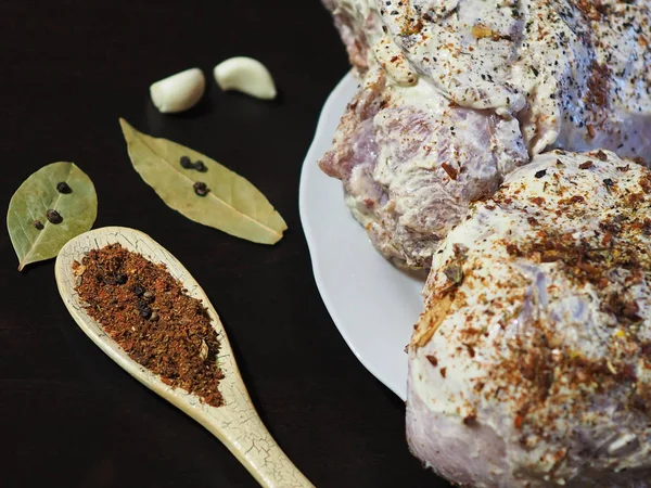 Mix fragrant spices in the original spoon on the background of raw meat in the marinade close-up.